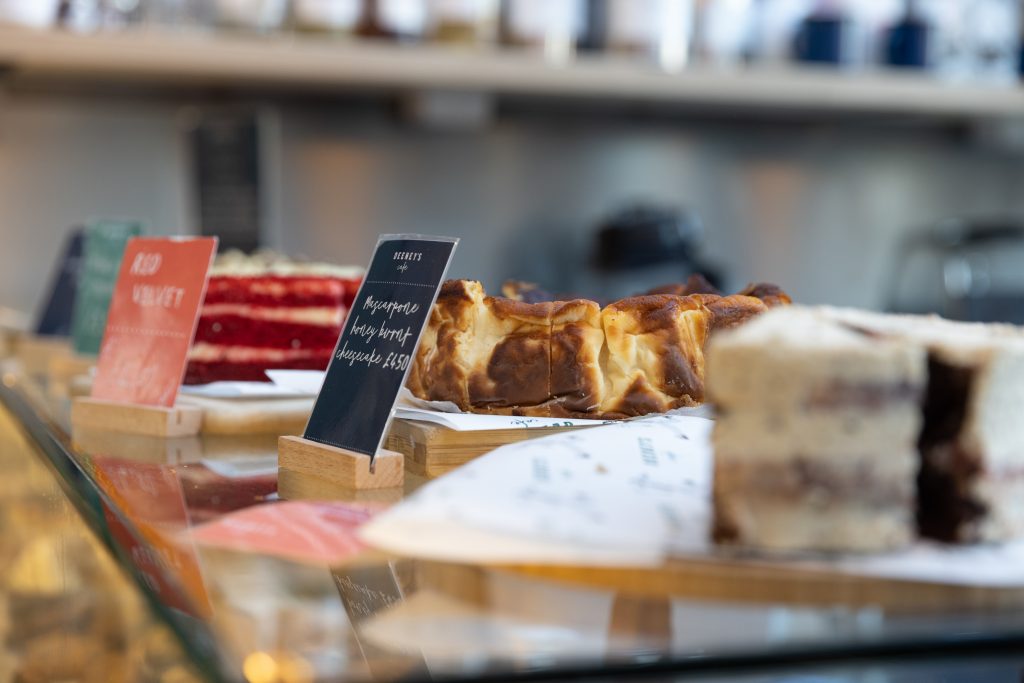 Images of cakes and pastries on top of the cafe's counter.