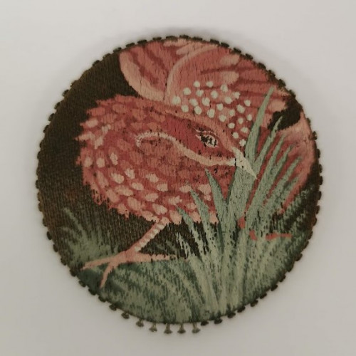 Dark circle with a pink bird hiding in green grass