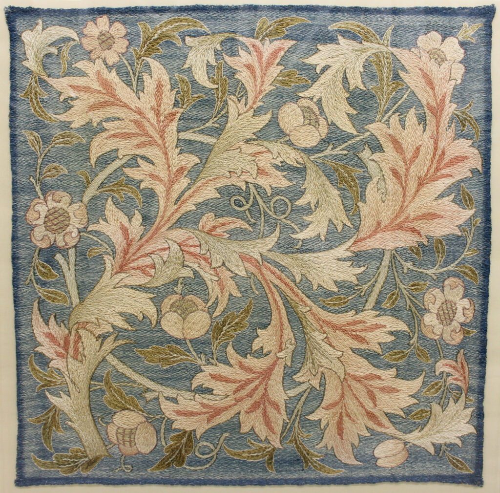 embroidery of pink scrolling leaves against blue stitched ground