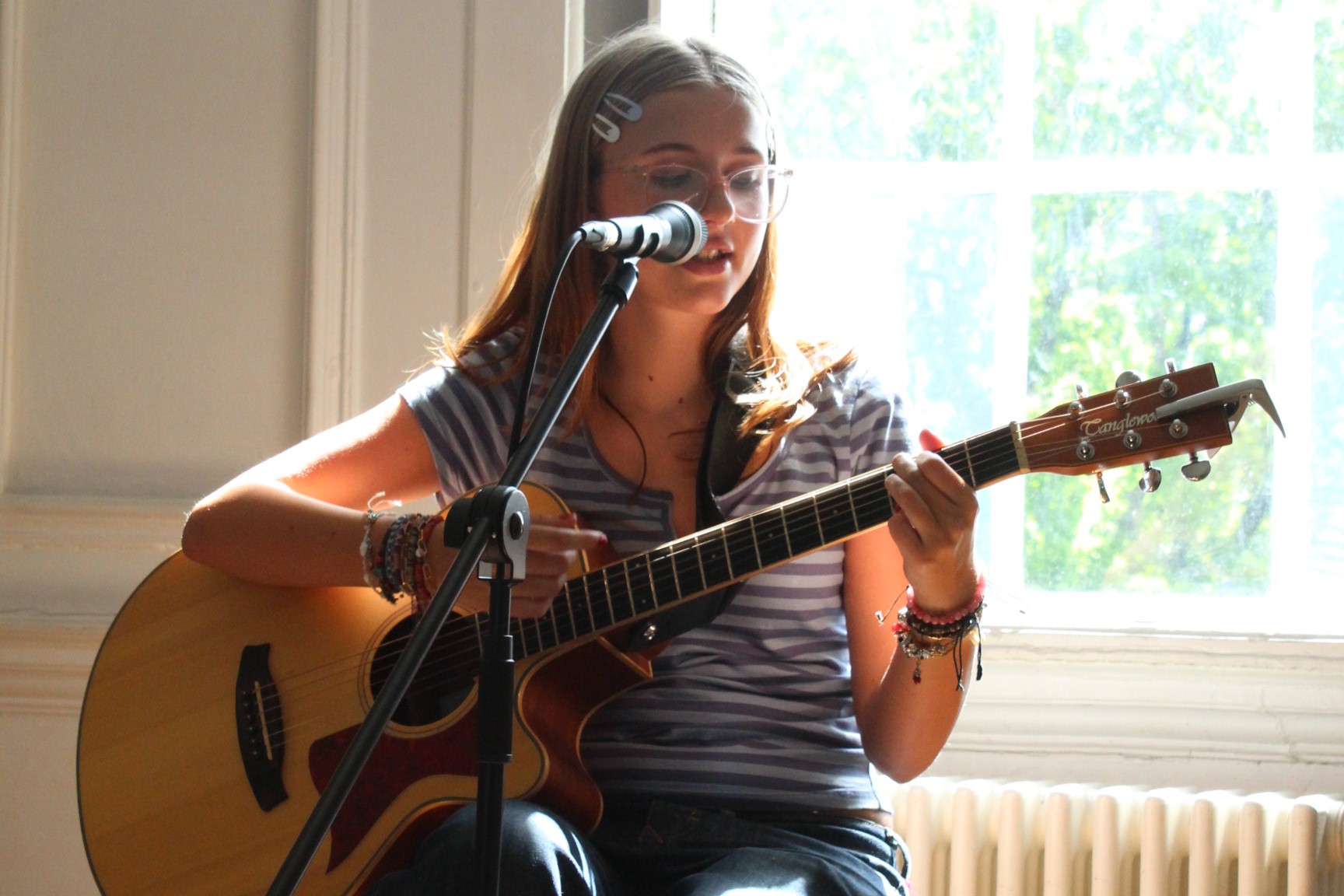 Performer sits to play guitar and sing